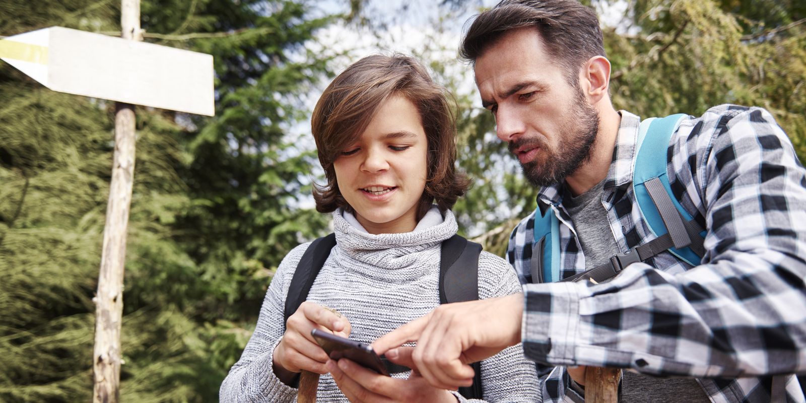 Père et fils consultant une application sur smartphone pendant une randonnée