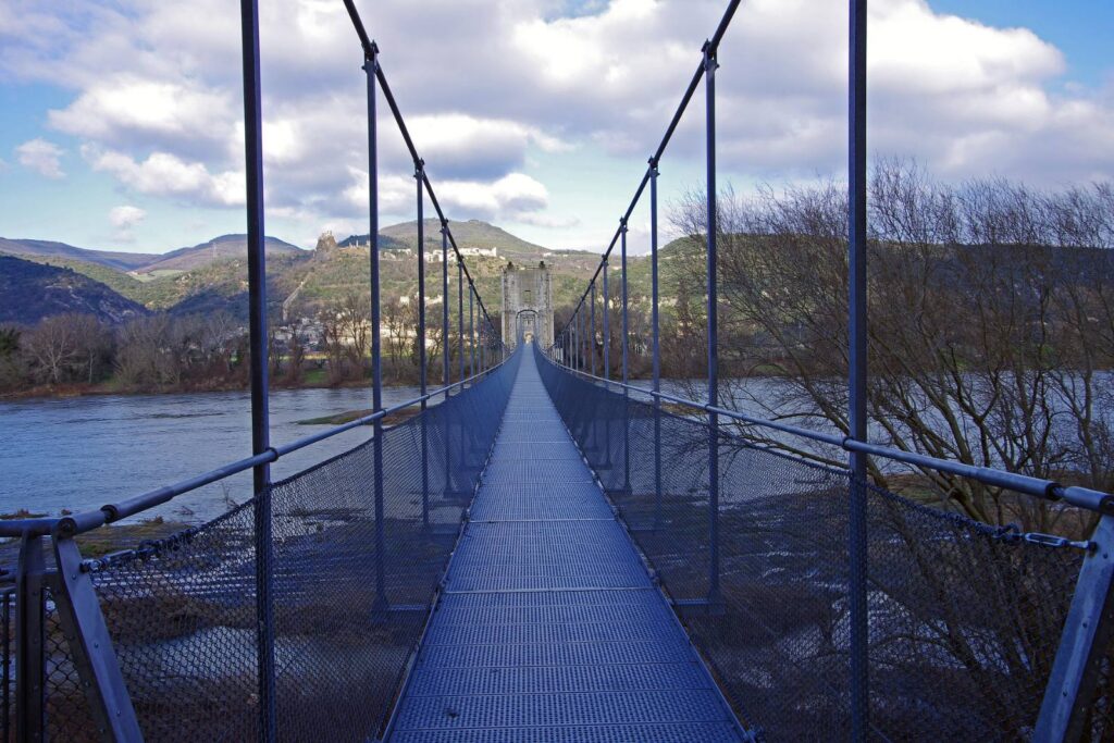 Brugdek van de hangbrug van Rochemaure tussen de kabels, met het dorp en het kasteel in de verte
